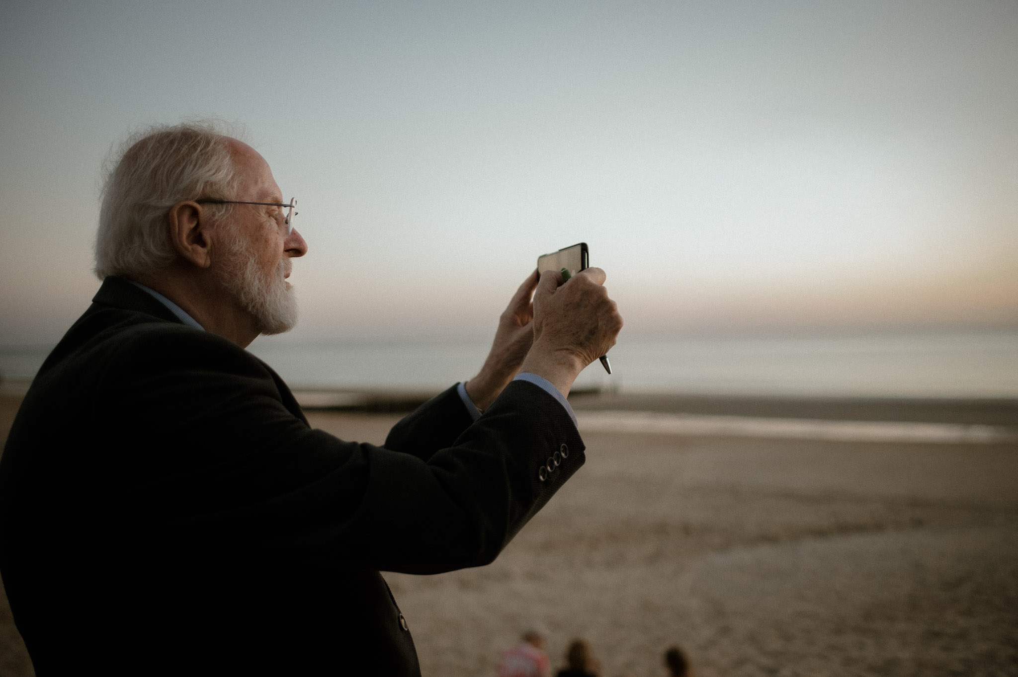 Een documentair fotograaf legt een opa vast die een foto maakt van de zonsondergang